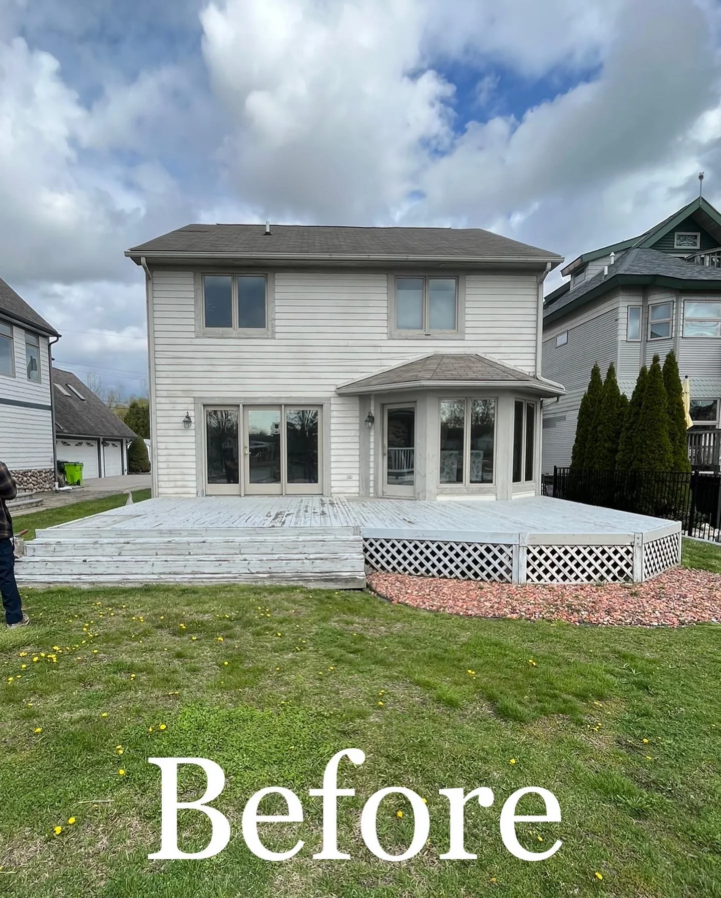 Plain colonial back exterior before remodel — white vinyl siding, basic concrete deck, and standard windows