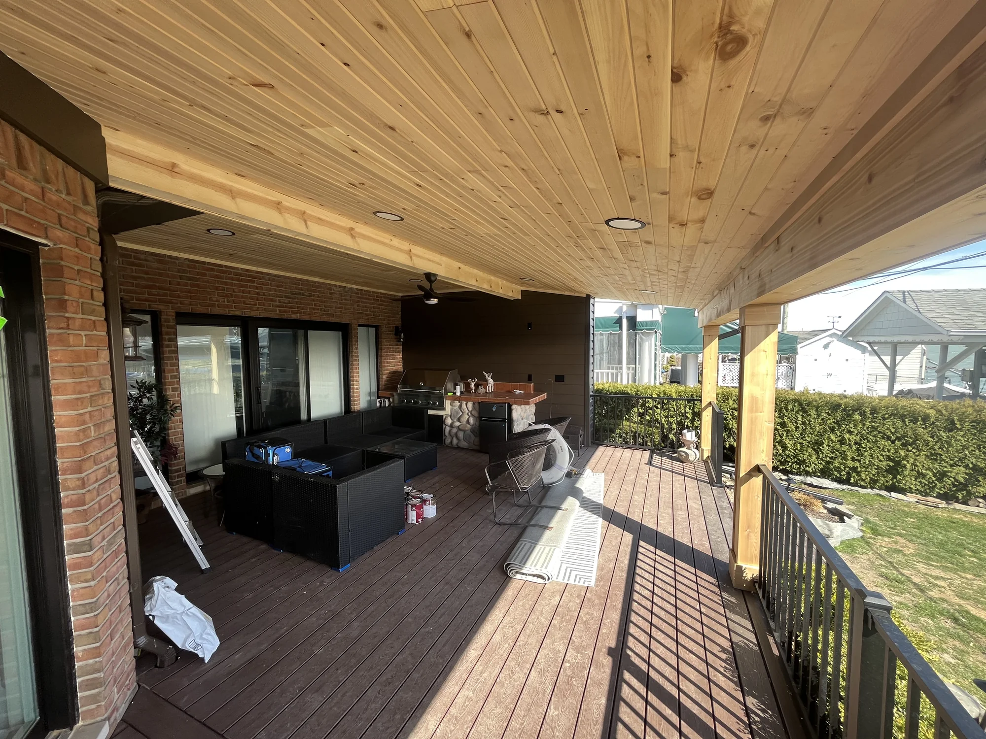 Covered porch with knotty pine ceiling, outdoor kitchen counter, composite decking, and lounge seating