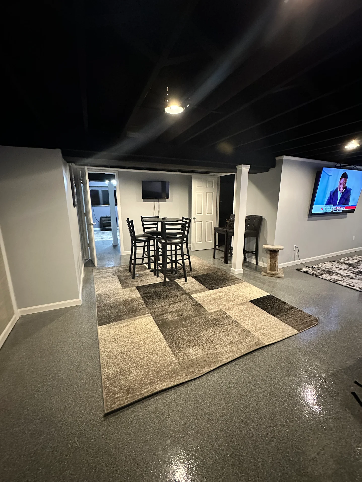Finished basement with epoxy floor and exposed black-painted ceiling