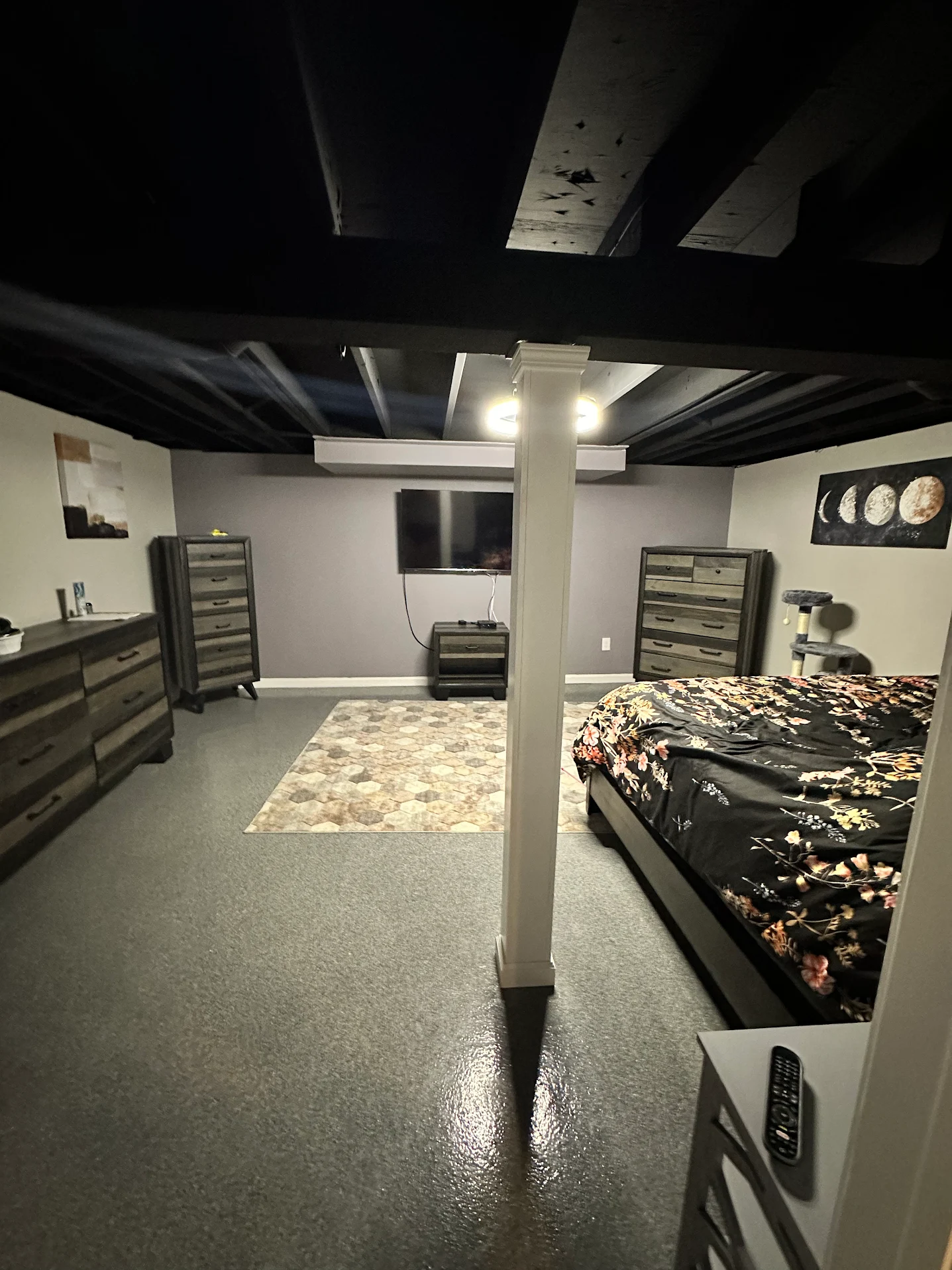 Basement primary suite with epoxy floor and black-painted exposed ceiling
